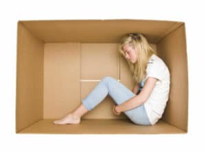 Woman siting in a cardboard box isolated on white background